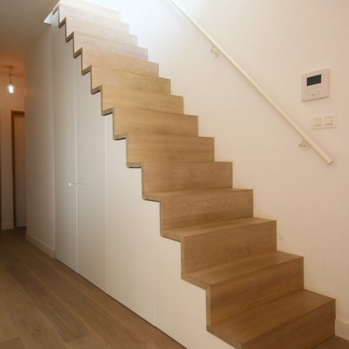 Onder deze trap creëerden we een kast op maat, zo gaat de plaats onder de trap niet verloren en oogt het geheel strak. Kast-ID Antwerpen